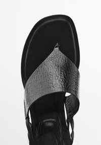 Zwarte sandaal met een gestructureerde leren strap, platte zool en een teenslipperontwerp. De voetbed is glad, wat zorgt voor een minimalistische uitstraling.