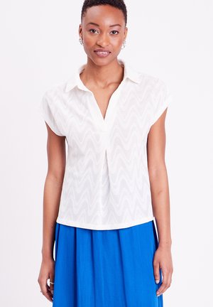 Blusa bianca a maniche corte con un motivo testurizzato ondulato, design con colletto e una vestibilità comoda, abbinata a una gonna blu.