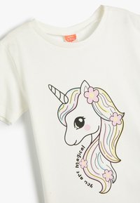 Hvid bomulds t-shirt med et enhjørning-graphic med en farverig manke og blomster, prydet med teksten "Du er magisk."