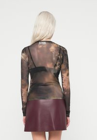 Μακρυμάνικο, διαφανές μπλουζάκι από δίχτυ που διαθέτει σχέδιο tie-dye σε γήινες αποχρώσεις. Συνδυασμένο με μίνι φούστα από μπόρντο δέρμα.