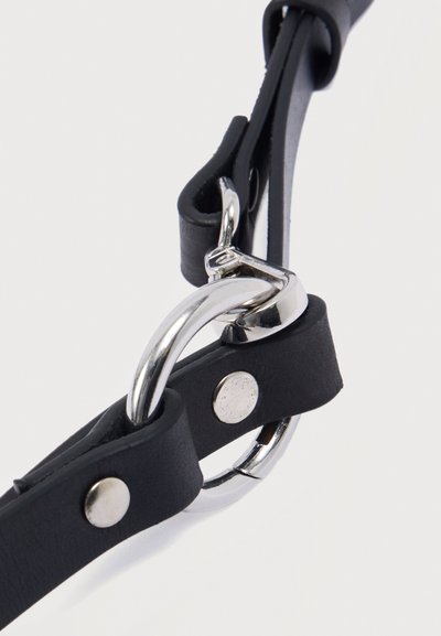 Μαύρο δερμάτινο λουράκι με λαμπερό ασημί μεταλλικό δαχτυλίδι και κουμπώματα τύπου snap, με λεία υφή και μινιμαλιστικό σχεδιασμό.