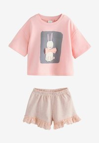 Rosa bomullströja med korta ärmar och kanin grafik; ihop med shorts med volangkant i en ljusare rosa nyans.
