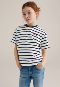 Dryžuotas t-shirt balta spalva su tamsiai mėlynomis horizontaliomis juostelėmis, turintis tamsiai mėlyną apvalų kaklą ir raudoną išsiuvinėtą tekstą krūtinėje. Kasdienis siluetas.