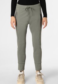 Slim-fit joggers i olivgrön, tillverkade av ett strukturerat material. Har en dragsko i midjan och fickor med dragkedja på båda sidor.