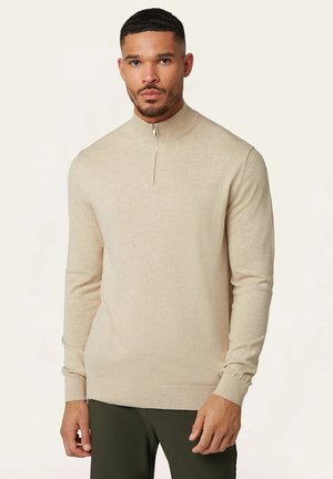Beige Reißverschluss-Pullover aus weichem Material, mit hohem Kragen, gerippten Bündchen und einem einfachen, nahtlosen Design. Figurnaher Schnitt mit langen Ärmeln.