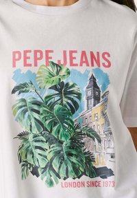 Camisa blanca con grandes hojas tropicales verdes, edificios de Londres, el reloj Big Ben y el texto "PEPE JEANS LONDON SINCE 1973" en rojo.