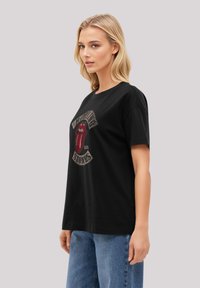 Black cotton t-shirt featuring a large graphic of the Rolling Stones' iconic red lips logo with a vintage-style banner reading "Rolling Stones."