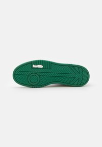 Suola di sneakers in gomma verde con motivo a spina di pesce testurizzato, presenta un logo circolare e bordi rinforzati, progettata per aderenza e durata.
