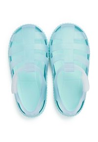 Translucente lichtblauwe sandalen met een gestructureerd ontwerp, textuurzolen en een achterband voor een veilige pasvorm. Gemaakt van flexibel plastic materiaal.