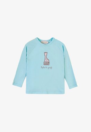 Camicia a maniche lunghe azzurro chiaro realizzata in tessuto morbido, con un design di giraffa ricamato in marrone e del testo sottostante. Collo rotondo e maniche raglan.