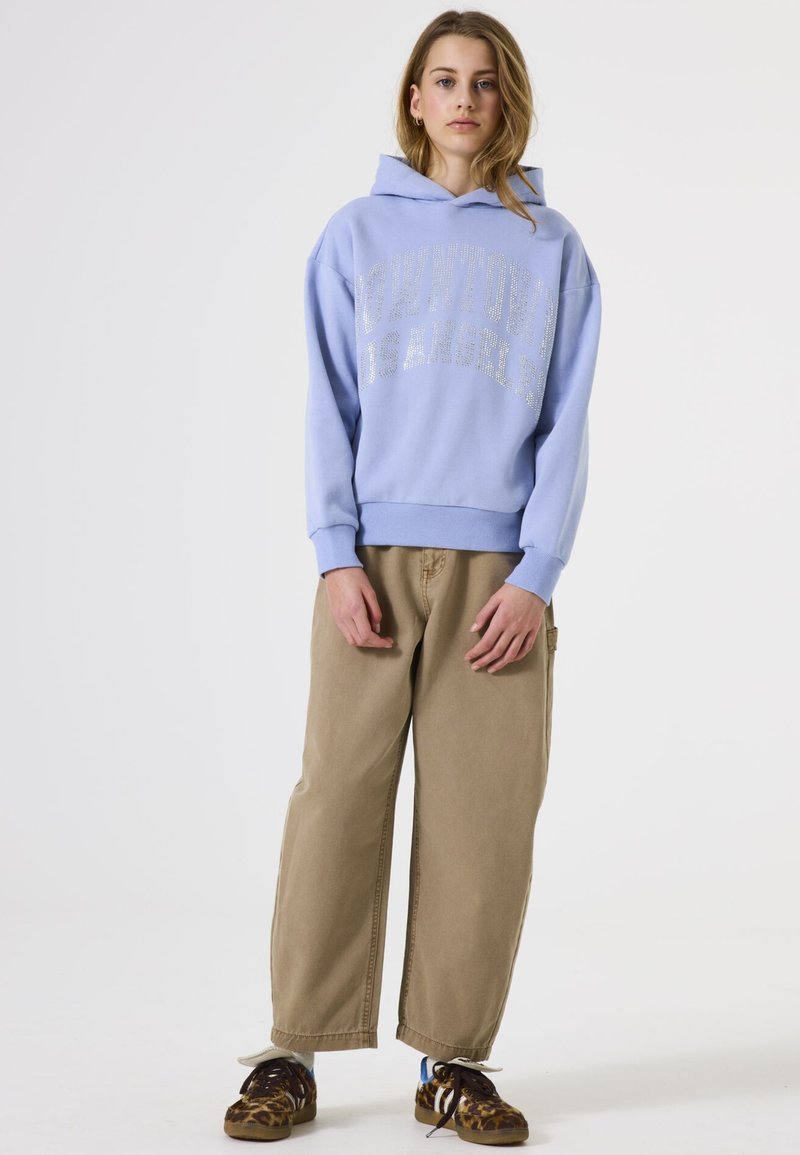 Sudadera azul claro con letras en impresión plateada, combinada con pantalones de pierna ancha beige y zapatillas de leopardo. Tejido casual de mezcla de algodón.