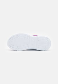 Semelle de sneaker blanche avec des motifs de grip texturés. Elle présente une forme lisse et arrondie et une étiquette d'accent rose près du talon.