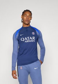 Navy long-sleeve sports top with blue accents, quarter-zip neck, and white "Qatar Airways" logo; paired with blue athletic pants.