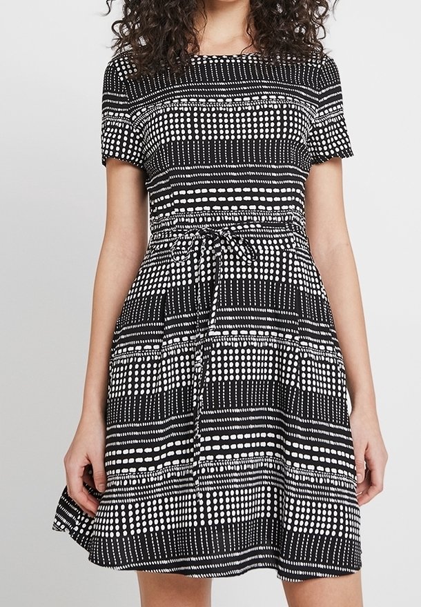 Svart och vit mönstrad klänning med korta ärmar, en figursydd bodice och en utsvängd kjol med dragsko i midjan.
