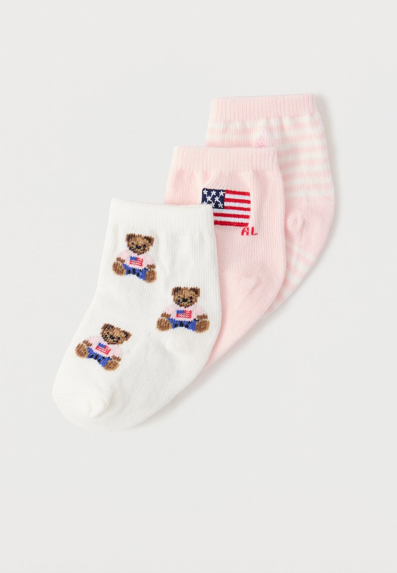 Τρία ζευγάρια παιδικές κάλτσες σε λευκό με αρκουδάκια, ροζ με τη σημαία των Ηνωμένων Πολιτειών, και ροζ με λευκές ριγές, τοποθετημένα επικαλυπτόμενα.