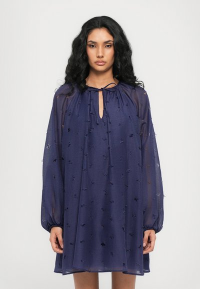 Navyblauwe chiffon jurk met een sleutelgat halslijn, lange ballonmouwen en geborduurde bloemendetails. Gladde, lichte textuur.