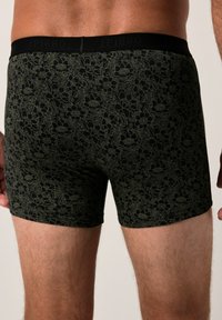 Boxers noirs à motif floral vert foncé. Ceinture élastique avec le logo "JP1880". Taille ajustée et texture lisse.