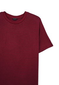 T-shirt bordeaux a maniche corte realizzato in tessuto testurizzato, con scollatura rotonda e vestibilità leggermente ampia. Etichetta visibile al colletto.