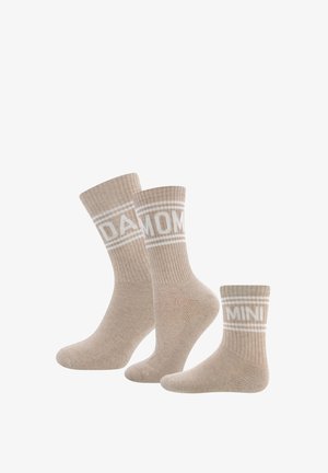 Beige Baumwollsocken in drei Größen, mit geripptem Muster, weißen Streifenakzenten und den Aufschriften "PAPA", "MAMA" und "MINI" an den Bündchen.