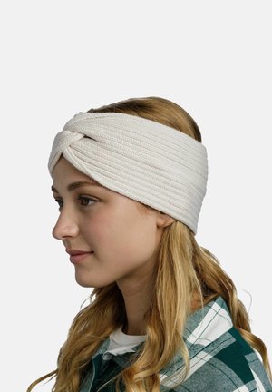 Knotiges weißes Stoffhaarband mit strukturiertem Oberflächen, getragen auf dem Kopf eines Modells. Langes, welliges Haar sichtbar, getragen mit einem grün karierten Hemd.