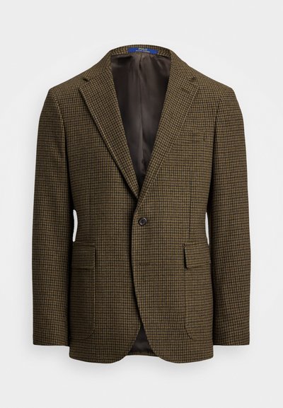 Ruskea houndstooth-takki, jossa on viilto-osa, yksittäinen nappikiinnitys, kaksi etutaskua ja sileä sisävuori. Normaali istuvuus.