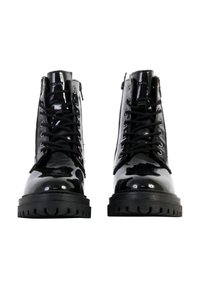Botas de charol negras con cordones, suela de goma gruesa y detalles texturizados en la parte superior. La vista frontal muestra una superficie brillante y una puntera redonda.