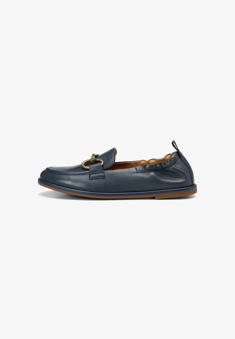 Mocassin en cuir bleu marine avec un dos élastique, une semelle marron et une boucle décorative en métal doré sur le dessus.