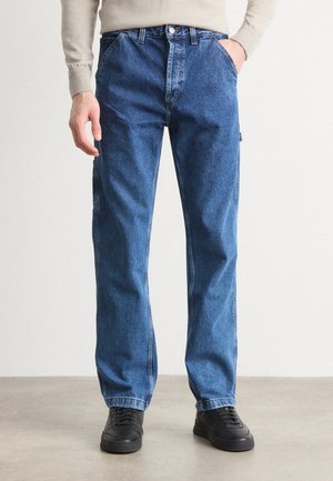Jean en denim bleu avec une coupe droite, présentant un design classique à cinq poches, une fermeture à bouton en métal et un léger dégradé sur le tissu.