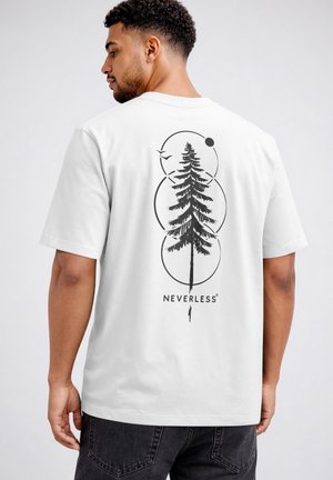 Man wearing white T-shirt with black graphic of tall pine tree, three circles, a bird, and the word "NEVERLESS" on the back.