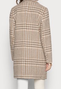 Lungo cappotto marrone a scacchi con un design strutturato, caratterizzato da un colletto, maniche lunghe e tessuto testurizzato, mostrato da dietro.