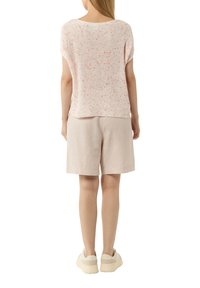 Hellrosa gestricktes Oberteil mit gesprenkeltem Muster, kurzen Ärmeln, runder Ausschnitt, kombiniert mit beigen Shorts und cremefarbenen Sneakers.