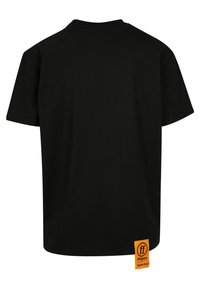 Camiseta de algodón negra con un corte holgado, cuello redondo y mangas cortas. Presenta una etiqueta naranja prominente en la costura lateral inferior.