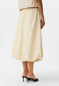 Crème-kleurige rok met een elastische tailleband, met een volumineuze, geraffineerde silhouet. Gekocht met zwarte open teen hakken.
