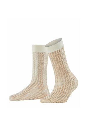 Paire de chaussettes en maille beige avec des bord-côtes élastiques blancs présentées sur des mannequins de pieds transparents sur fond blanc.