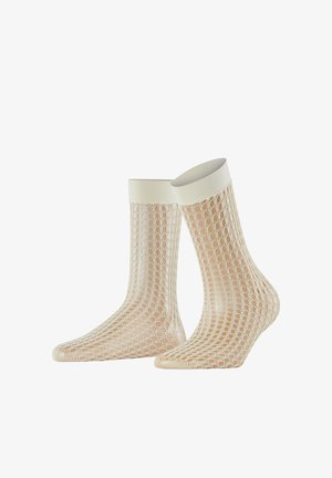 Paire de chaussettes en maille beige avec des bord-côtes élastiques blancs présentées sur des mannequins de pieds transparents sur fond blanc.