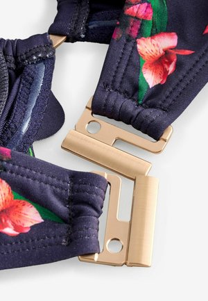 Blomsterprint justerbare stropper i mørkeblå stof med guldfarvede metalbeslag og elastiske detaljer for fleksibilitet og komfort.