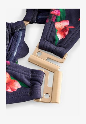 Blomsterprint justerbare stropper i mørkeblå stof med guldfarvede metalbeslag og elastiske detaljer for fleksibilitet og komfort.