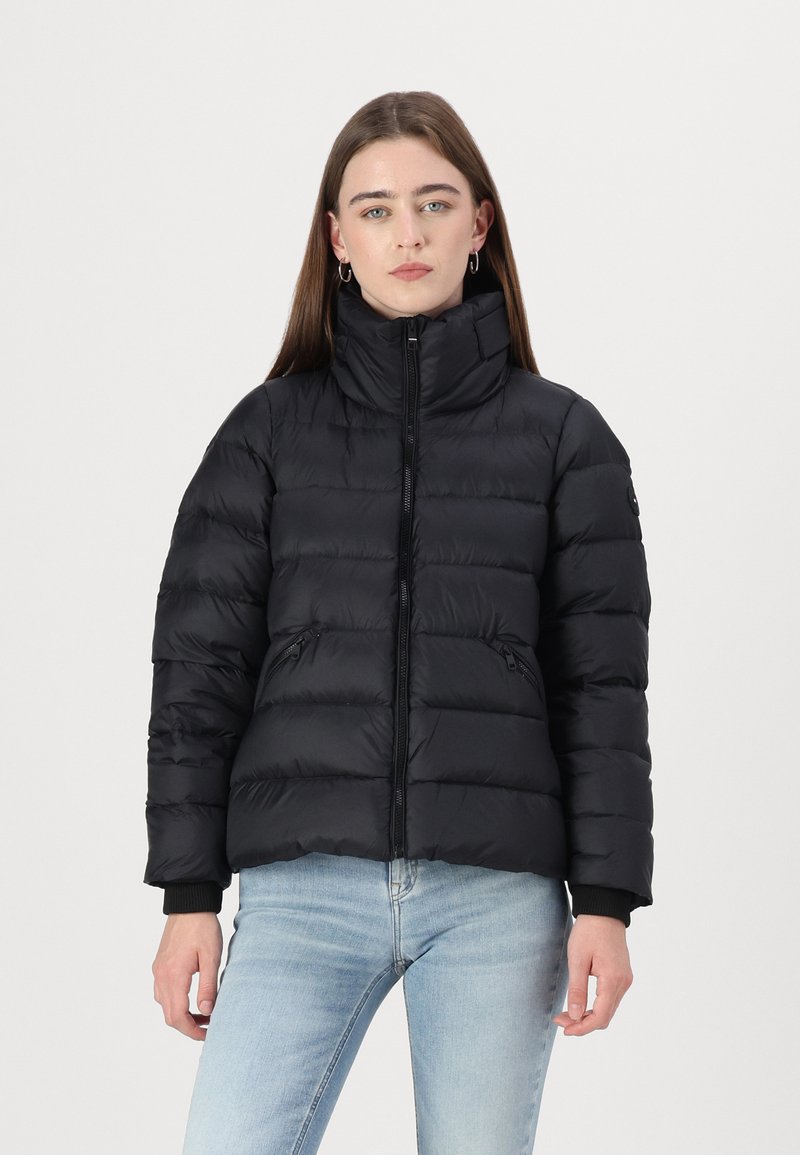 Swarte puffjakke med høy krage, frontglidelås og sidelommer. Har quiltede seksjoner og ribbede mansjetter. Jevn, matt tekstur.