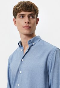 Lichtblauw overhemd met knopen en een klassieke kraag, voorzien van witte knopen en een gestructureerde stof. Slim fit, lange mouwen.
