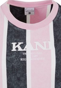 Pink, black, and white striped sweatshirt with a crew neck. Features embroidered "KANI" logo and soft, textured fabric.