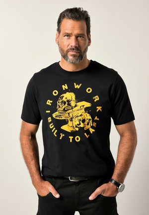 Sort bomulds t-shirt med et gult grafisk design med kranier og et ambolt, omkranset af teksten "IRONWORK IS BUILT TO LAST."