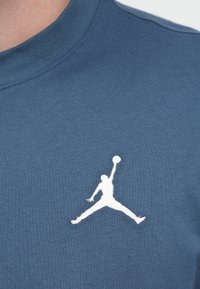 Μπλε βαμβακερό φούτερ με λευκό κεντημένο λογότυπο Jumpman στο στήθος, με στρογγυλή λαιμόκοψη και λεπτομέρειες υφής στο ύφασμα.