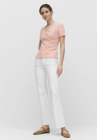 Lys rosa tekstureret top med korte ærmer og V-hals. Sat sammen med høj talje hvide lige bukser og beige flade sko.