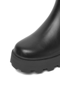 Černá kožená kotníková bota s kulatou špičkou, robustní podešví a texturovaným povrchem. Obsahuje silnou, odolnou podrážku pro lepší přilnavost.