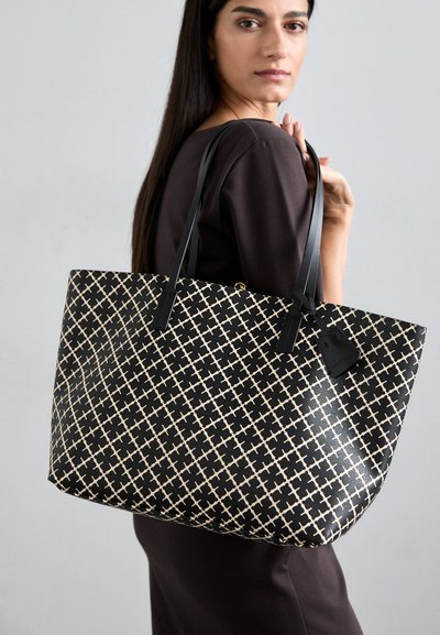 Large tote bag in black and beige fabric with a geometric cross pattern. Features black leather handles and a detachable tag.