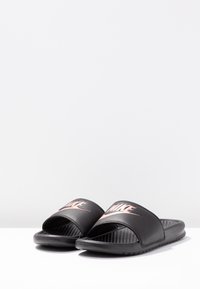 Black athletic slide sandals with a thick strap featuring a rose gold logo, textured footbed, and flexible rubber sole.