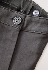 Sivé nohavice s hladkou textúrou, vybavené kovovým gombíkom na zapínanie a kontrastným prešívaním na páse a vreckách.