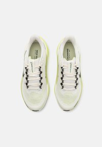 Chaussures de course légères en maille blanche avec accents noirs. Caractéristiques d'une semelle jaune fluo et d'un design à lacets. Texturé pour la respirabilité.