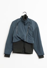 Mörk teal jacka med hög krage, med två dragkedjeförsedda bröstfickor och svarta axlar och muddar. Slätt, flexibelt material.