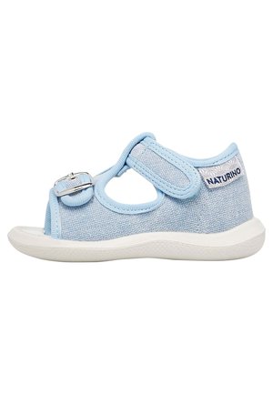 Sandale en tissu bleu clair avec bout ouvert, sangle réglable et semelle en caoutchouc blanche. Présente un tissu texturé et le logo "Naturino" sur le talon.